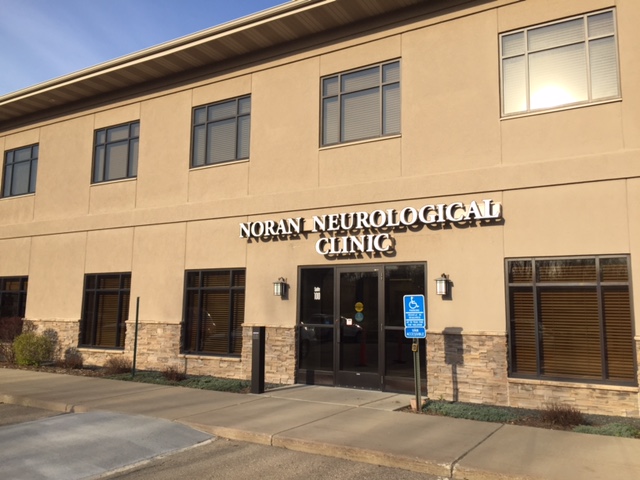 A two-story building with a sign reading "Noran Neurological Clinic" above the entrance. There is a handicap parking sign near the entrance.