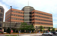 A multi-story brick and glass office building with a central tower and surrounding greenery.